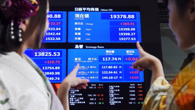 東京証券取引所の大発会に晴れ着姿で参加した女性と、年初の日経平均株価等の動きを示すボード=2017年1月4日、竹内紀臣撮影