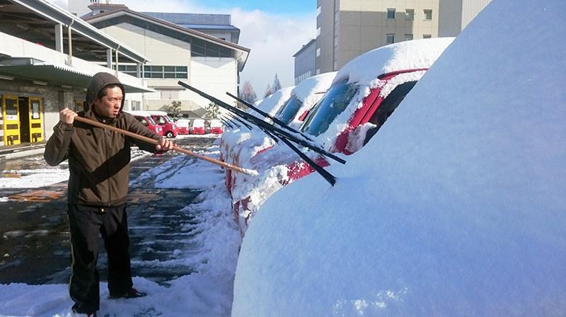 大津中央郵便局の駐車場で車に積もった雪をはらう男性=大津市打出浜で、太田裕之撮影