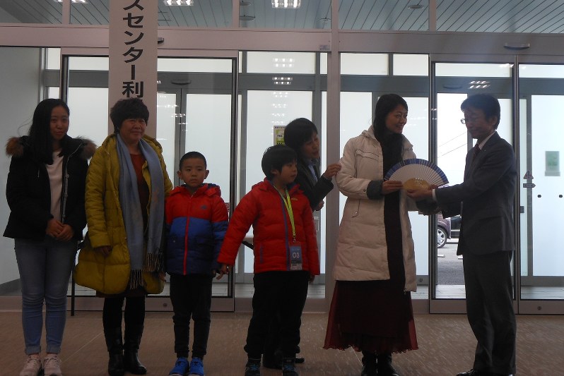 中央ふ頭クルーズセンターの100万人目の利用客となった梅さん(右から2人目)に記念の扇子を手渡す則松・市港湾空港局長
