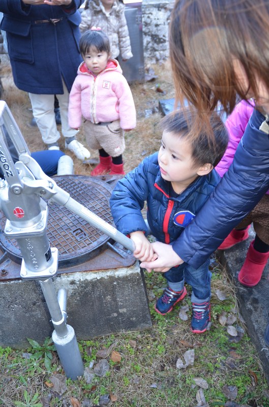 防災井戸で水くみを体験する親子たち=江南市の愛知江南短大で