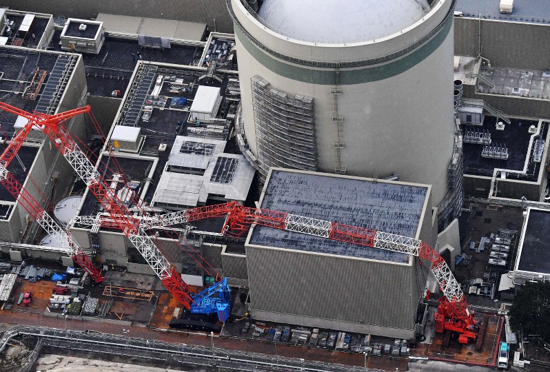 関西電力高浜原発2号機の燃料取り扱い建屋(右)と原子炉補助建屋に倒れたクレーン=福井県高浜町で2017年1月21日午前9時25分、本社ヘリから小関勉撮影