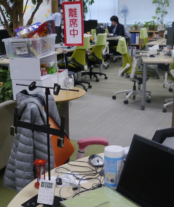 アクロクエストテクノロジーで喫煙対策に効果があった離席中の旗。パソコンの脇のタイマーで7分以内に帰ってこないと罰金がとられる=横浜市港北区の同社で