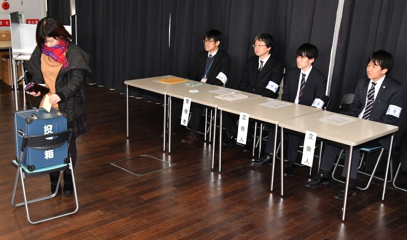 立会人を務めた学生(右端と右から2人目)が見守る前で投票する北九大生
