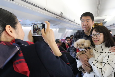 ＪＡＬ１１１１便の機内で愛犬とともに記念撮影をしてもらう参加者＝２０１７年１月２７日、米田堅持撮影