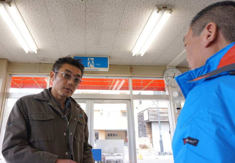 販売店の従業員と新聞配達の打ち合わせをする林富士雄さん(左)=福島県浪江町権現堂の浪江新聞販売センターで2017年2月7日、大塚卓也撮影