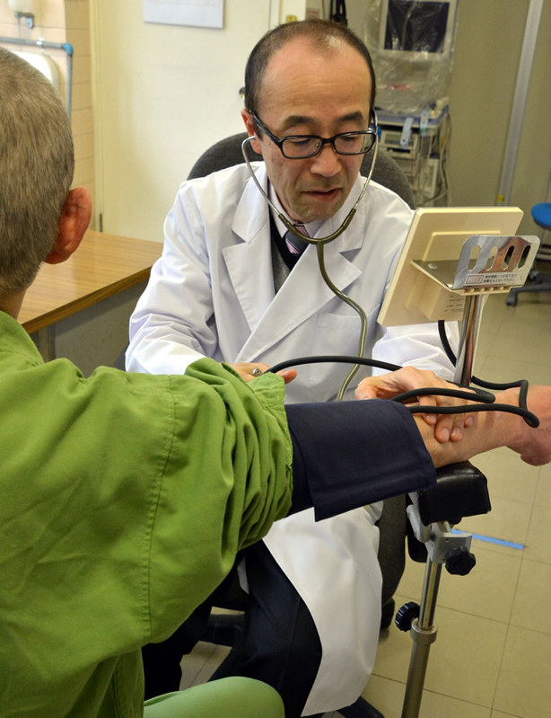 受刑者を診察する池田正行さん(右)=高松市の高松刑務所で、岩崎邦宏撮影