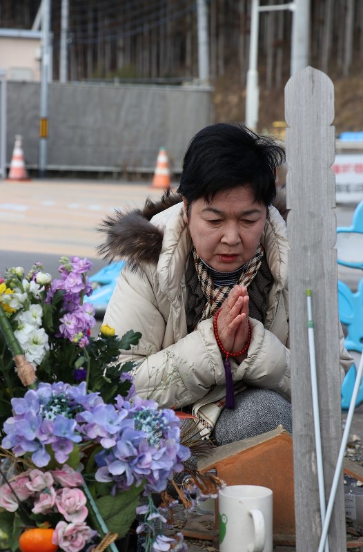 消防署の跡地で手を合わせる佐藤さん=宮城県南三陸町志津川で2017年2月11日、根本太一撮影