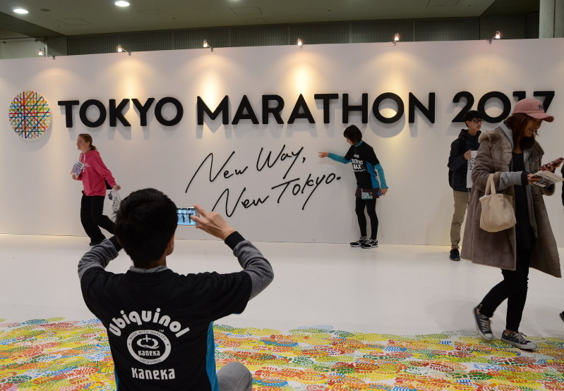 「TOKYO MARATHON 2017」と書かれた壁の前で、記念撮影するランナーたち=2017年2月24日、中嶋真希撮影