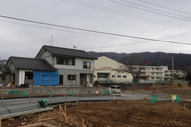 市庁舎の建設候補地にあがっている小学校(右)。1階が浸水した手前の住宅は震災から間もなく6年になる今も当時の姿のままだ=岩手県陸前高田市で2017年2月1日、根本太一撮影