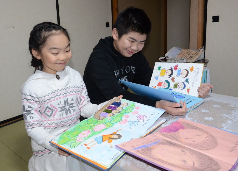 兄冬真さん(右)とともに作った絵本を読む平塚小瑛さん=仙台市内で、古川宗撮影