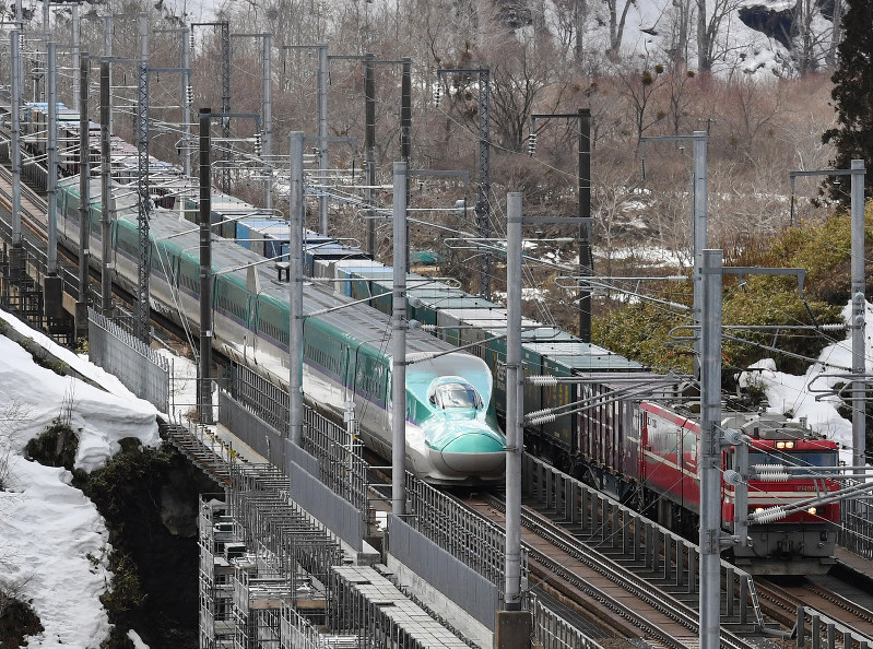 貨物列車とすれ違う北海道新幹線(左)=北海道知内町で25日、竹内幹撮影