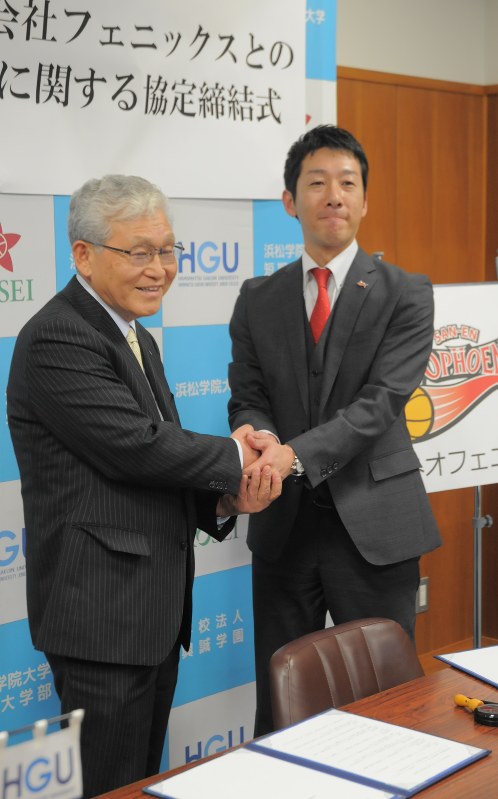 全面協力の協定書を交わし、握手する石田勝義学長(左)と浜武恭生社長=浜松市中区の浜松学院大で