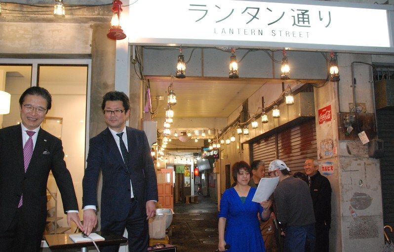 ランタン点灯のスイッチを押す前葉泰幸市長(左端)と近沢正浩理事長(左から2人目)=津市大門商店街で