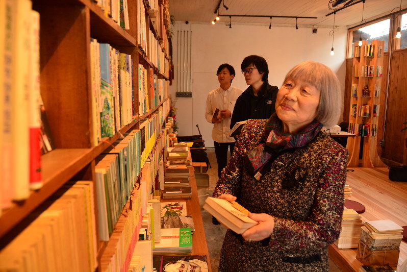 本を整理する原田伸子さん(手前)。東北芸工大の学生2人組(奥)が支援した=山形市七日町の「郁文堂書店」で