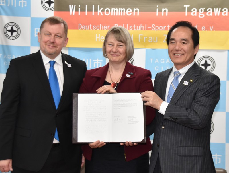 サインした文書を手にする二場市長(右)とドイツ車いすスポーツ連盟の関係者