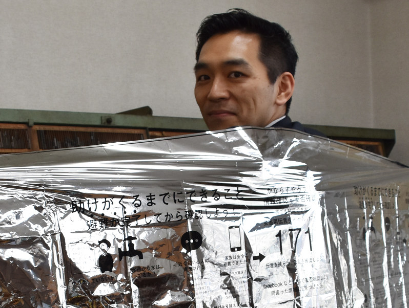 試作品のアルミシートをまとう高山社長=大分市片島で、安部志帆子撮影