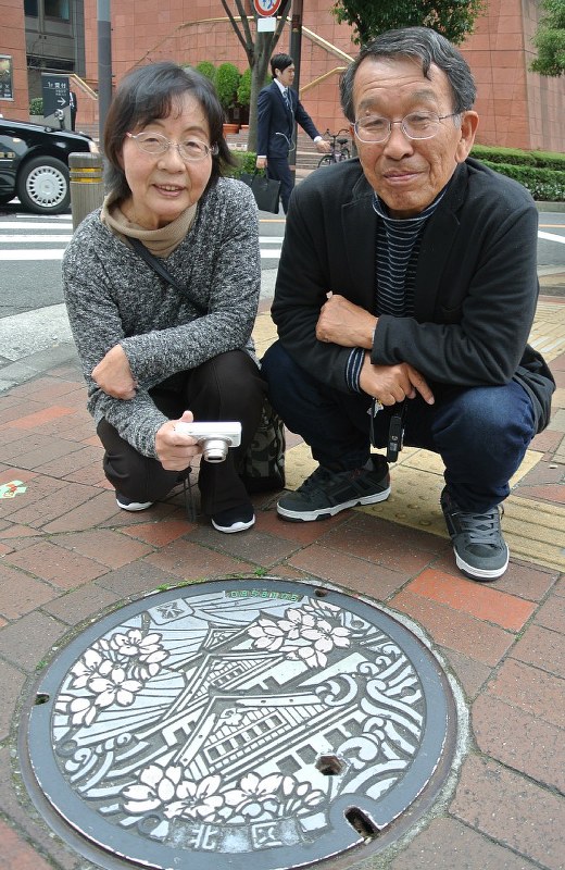 大阪城がデザインされたマンホールを見つけた池上和子さん(左)と修さん=大阪市北区で、倉田陶子撮影