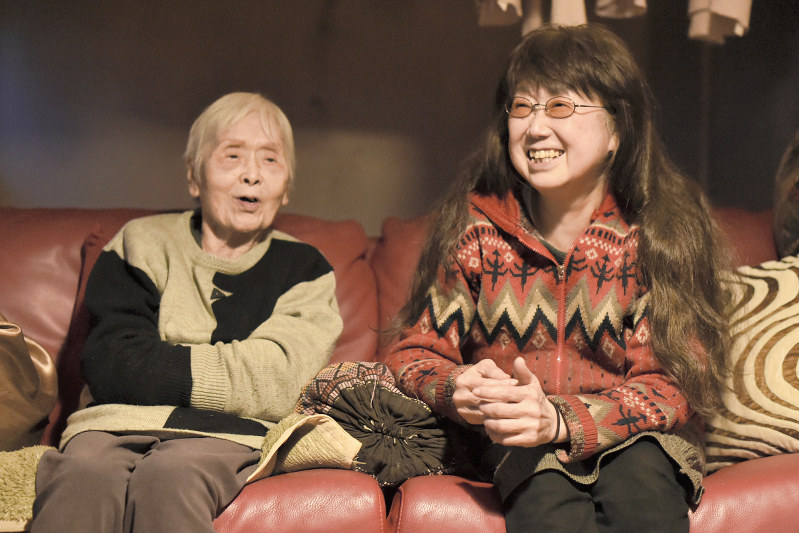 自宅のソファで酒井アサヨさん(左)の言葉に笑顔を見せる娘の章子さん=大阪市中央区で、三浦博之撮影