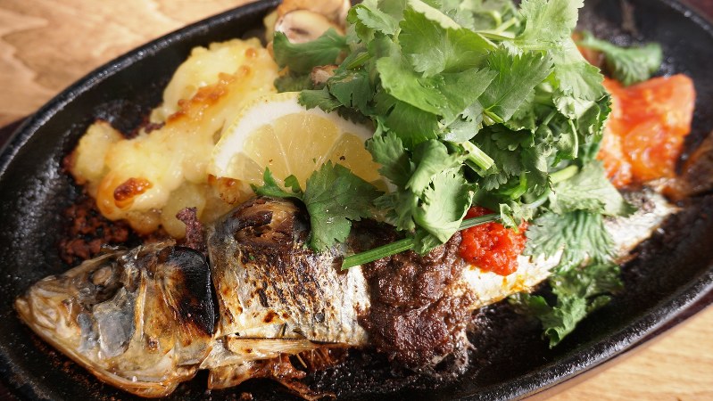熱々の鉄板皿で提供される「丸ごと1匹!いわしの焼きポテトサラダ ポルトガル風」(880円税別、以下同)