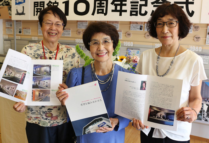 開館10周年記念誌を手にする野間美喜子館長(中央)と編集委員の赤沢ゆかりさん(右)、林和子さん