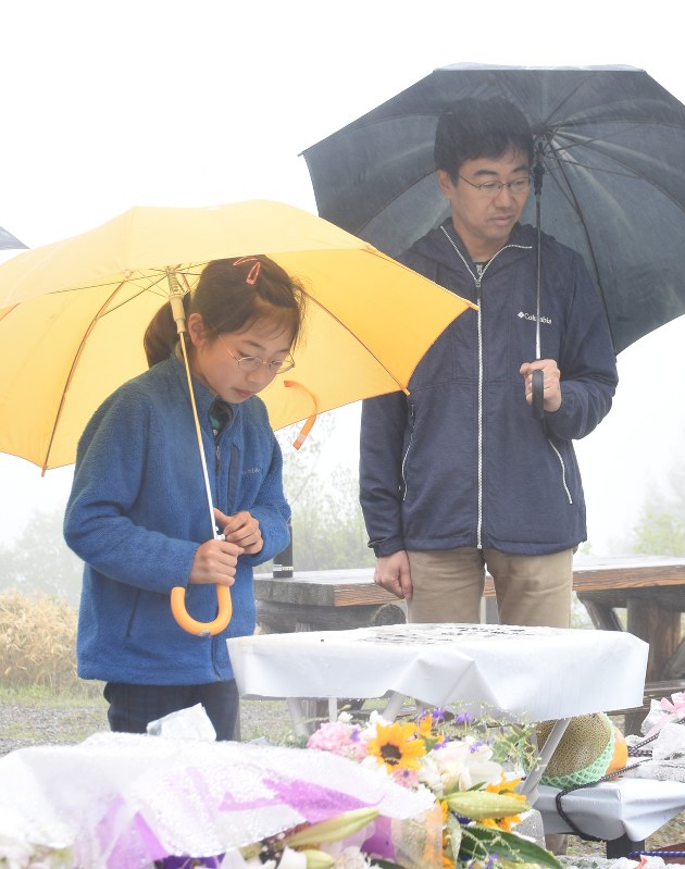雪崩事故現場近くの献花台で、亡くなった浅井譲さんを悼む父慎二さん(右)ら=那須町湯本で