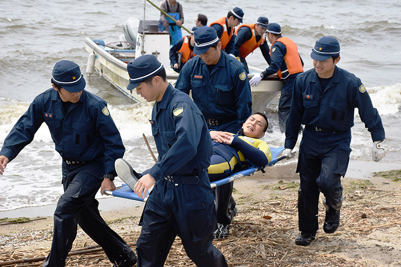 訓練で、漁船で救助された男性を担架で運ぶ警察官=松江市袖師町の宍道湖夕日スポットで、前田葵撮影