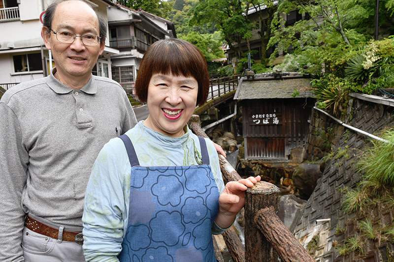 川沿いにある「つぼ湯」の湯小屋(右奥)と山根修さん、みや子さん夫妻=和歌山県田辺市本宮町湯峯で、藤田宰司撮影