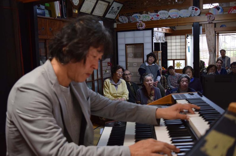 ミニコンサートで滝沢卓さん(手前)の演奏に聴き入る住民たち=宮古市の小笠原さん宅で