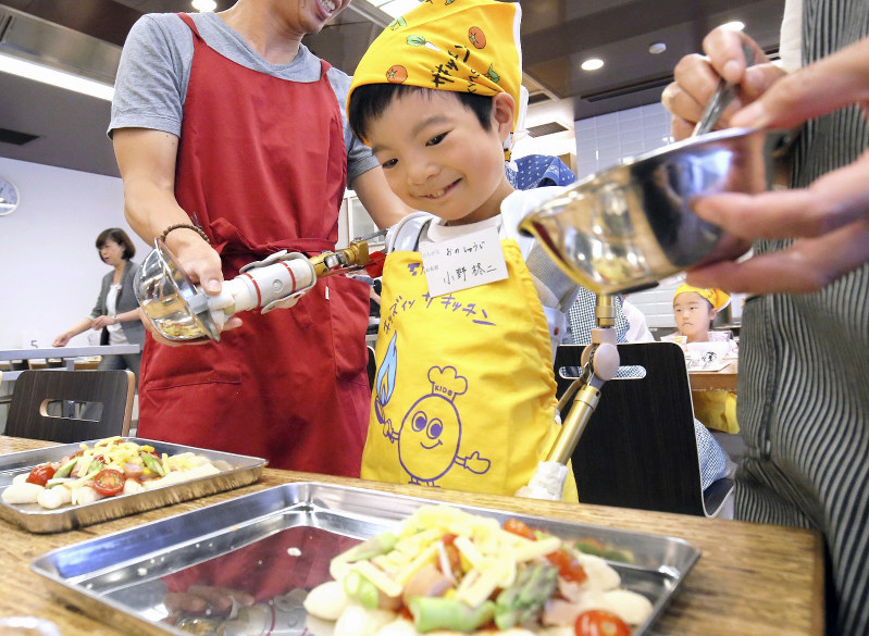 電動義手を使って料理する小野柊二さん=東京都中央区で2017年6月3日、宮武祐希撮影