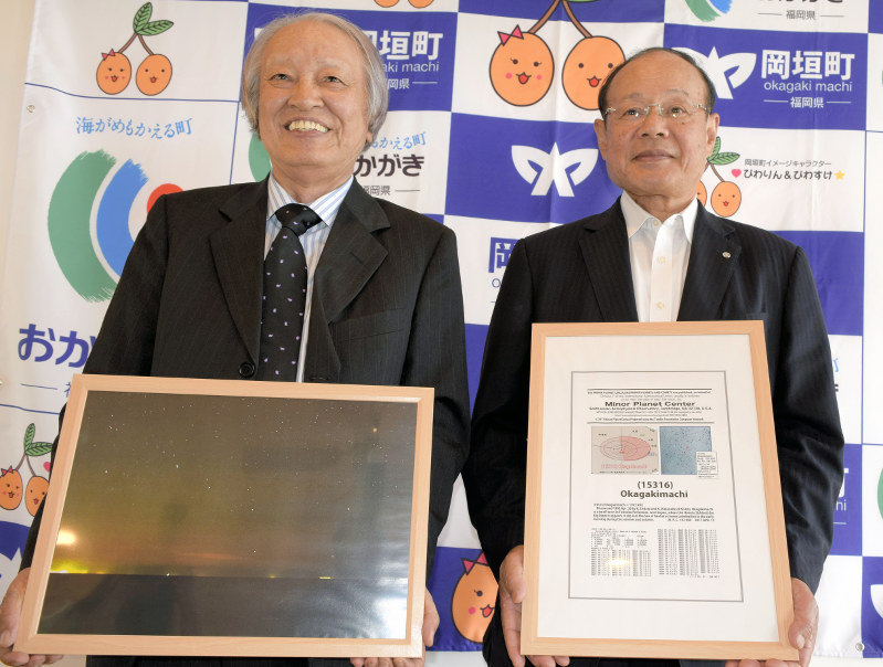 国際天文学連合が公表した小惑星「岡垣町」の回報を手にする宮内実生町長(右)と平井名誉教授=2017年6月1日、籔田尚之