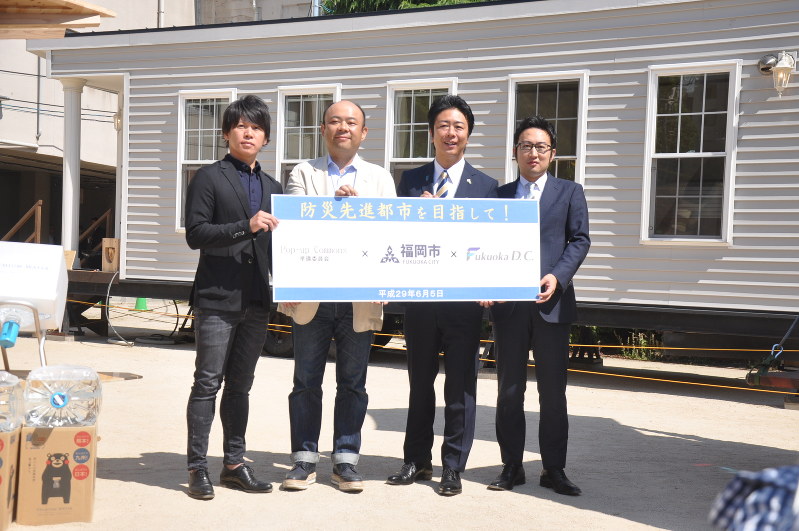 トレーラーハウスの前で記念撮影する孫委員長(左から2人目)と高島宗一郎市長(同3人目)ら