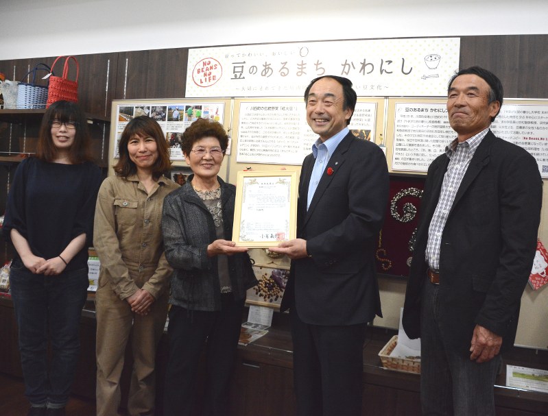 「マメリエ」の商標登録証をお披露目する「マメリエ」(左から3人)と原田俊二町長(同4人目)ら=川西町中小松の森のマルシェで