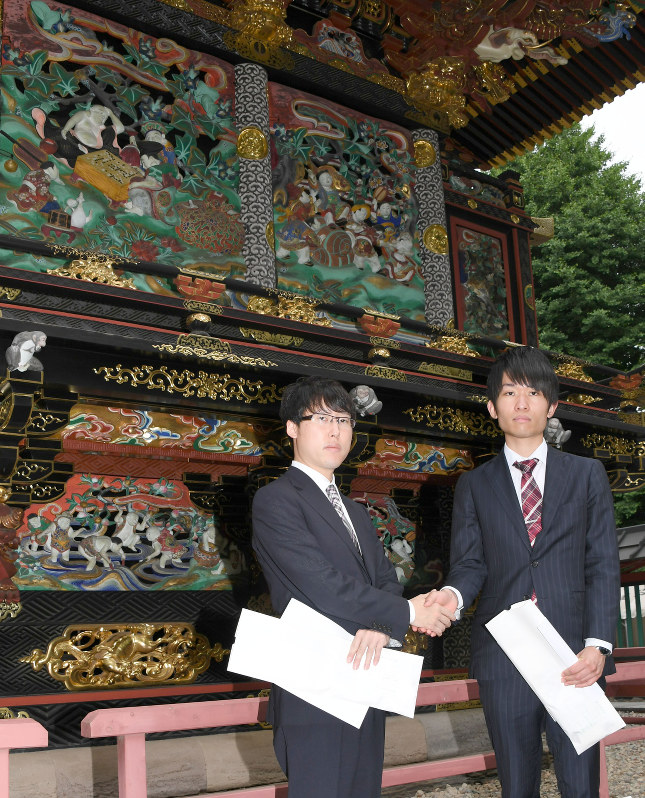 囲碁彫刻が施された国宝の本殿前で握手を交わす本因坊文裕(左)と挑戦者の本木克弥八段=熊谷市妻沼の聖天山歓喜院で、宮本明登撮影