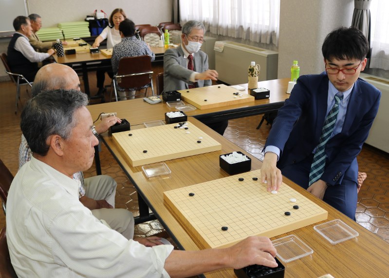 アマチュアの囲碁愛好者3人と同時に対局する平田智也七段(右)=熊谷市妻沼東の妻沼中央公民館で