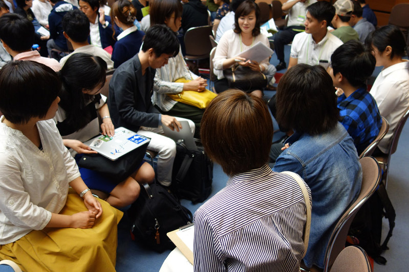 出展企業の担当者の話を聞く参加者たち=名古屋市中村区の名古屋国際センター別棟ホールで