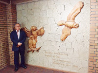 ミネルヴァ書房のシンボルマークであるフクロウのレリーフ前に立つ杉田啓三社長。右下には哲学者ヘーゲルの言葉がドイツ語で刻まれている=京都市山科区で、須藤唯哉撮影