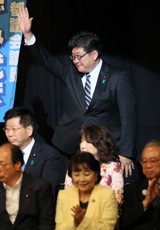 自民党都議の集会で手を上げて会場を後にする萩生田光一官房副長官=東京都葛飾区で2017年6月20日午後7時、佐々木順一撮影