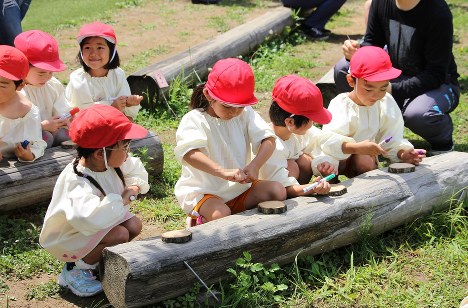 切り株に妖精の絵を描く園児たち