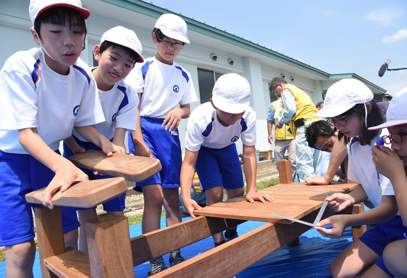 寄贈された木材で卒業制作のベンチづくりに取り組む渡波小の児童たち=石巻市渡波町の同小で