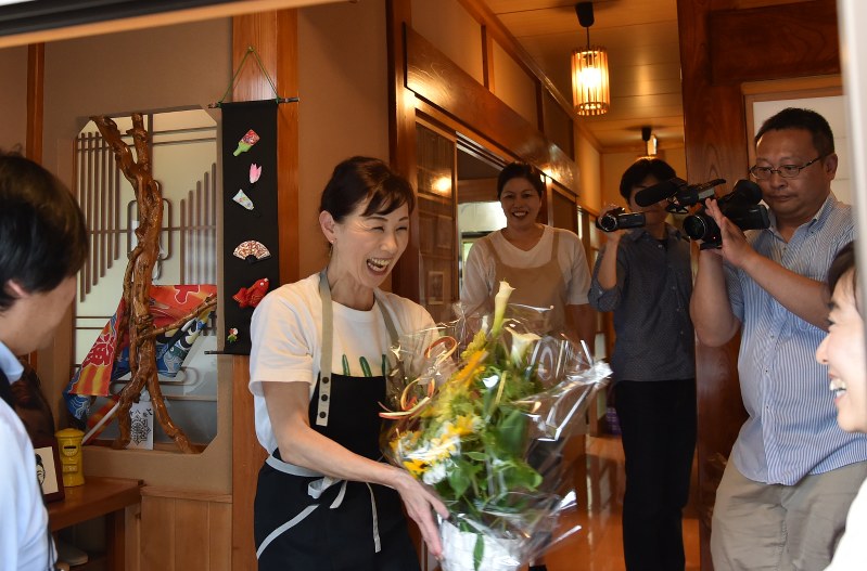 宿泊客から花のプレゼントを受け取り、笑顔を見せるおかみの菅野一代さん(左)=気仙沼市唐桑町で