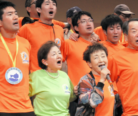 琵琶湖周航の歌音楽祭合唱コンクールで京都大ボート部OBらとマイクを持って歌う加藤登紀子さん(前列右から2人目)と、記念事業実行委員長の嘉田由紀子・前滋賀県知事(その左隣)=滋賀県高島市民会館で2017年6月25日、塚原和俊撮影
