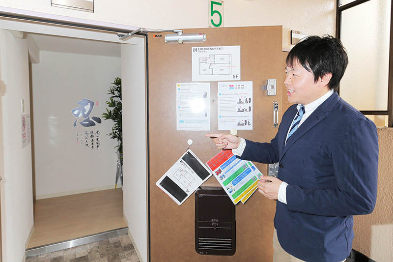 特区民泊として利用されているマンションの一室を案内するグローバルコムズジャパンの岸本和也社長。入り口ドアに避難経路や設備についての注意書きがある=大阪市中央区で、三村政司撮影