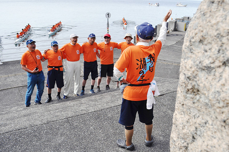 竹生島に上陸して歌碑(手前右)の前で琵琶湖周航の歌を歌う京都大ボート部OBら=滋賀県長浜市で、塚原和俊撮影