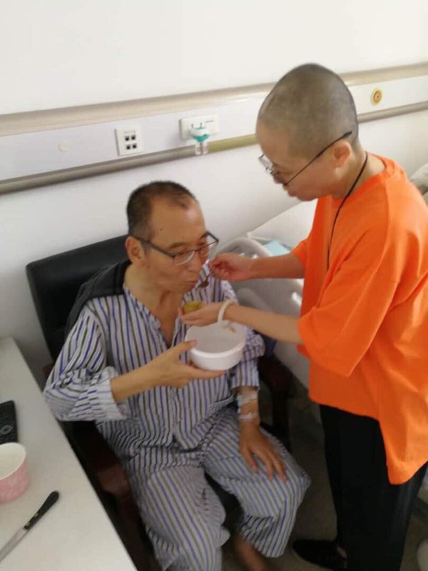 入院中の劉暁波氏(左)が妻霞さんの手助けで食事する様子とみられる写真=ツイッターから