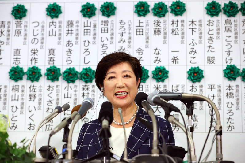 東京都議選で候補者の名前に緑色の花が並んだボードの前で笑顔を見せる小池百合子都知事=東京都新宿区で2017年7月2日午後8時57分、小川昌宏撮影