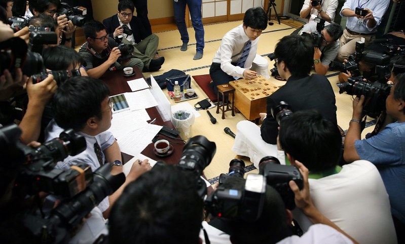 29連勝を達成し、多くの報道陣に囲まれる中、対局を振り返る藤井聡太四段(右奥)=東京都渋谷区の将棋会館で6月26日、佐々木順一撮影