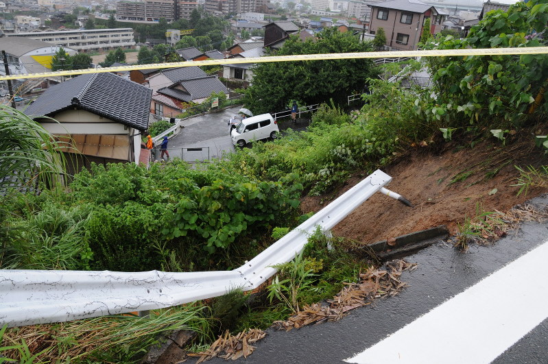 大雨の影響でガードレールや斜面が崩壊し、道路下の家屋を一部損壊させた=八幡東区帆柱で7日午後0時9分