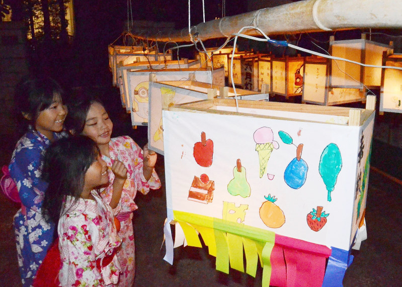 明かりを放つ灯籠の絵を楽しむ子供たち