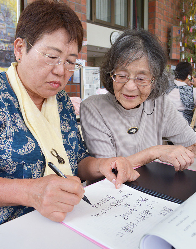 常木春枝さん(左)の要約筆記を読む山本篤子さん=三重県名張市で、竹内之浩撮影