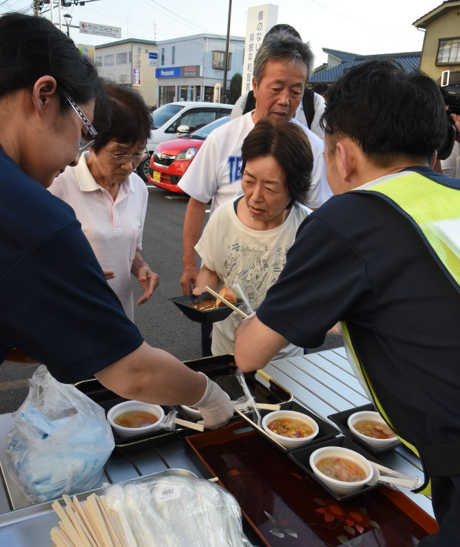 温かい料理を受け取る避難者温かい料理を受け取る避難者